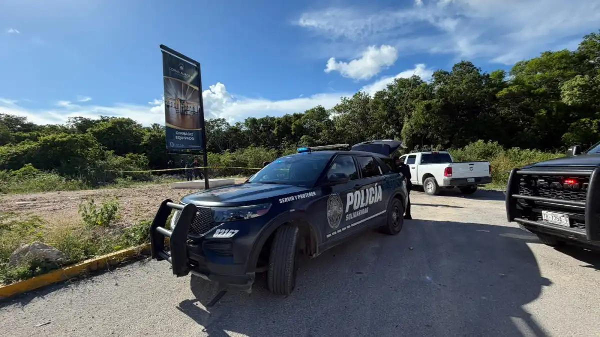 Viatura da polícia de Playa del Carmen parada ao lado de um terreno com mato isolado por fita, onde ocorreu uma das mortes