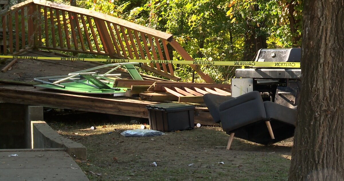 Deck de madeira desabado no quintal de uma casa, com guarda-corpo tombado, móveis espalhados e fita de isolamento