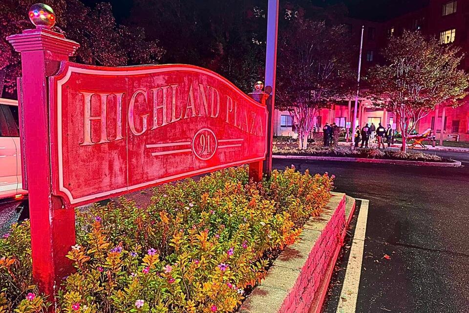 Placa do conjunto Highland Plaza, em Toms River, à noite, com equipes de resgate ao fundo