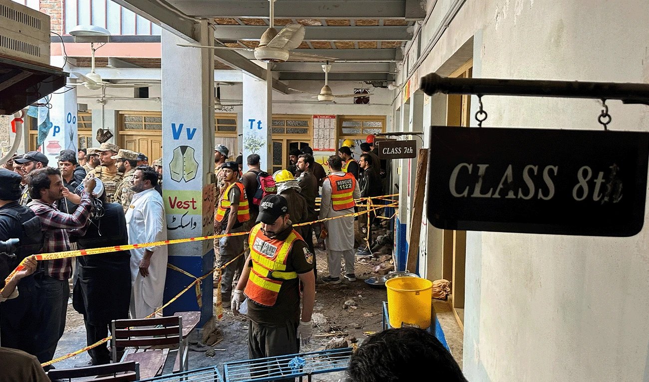 Soldados e socorristas do Rescue 1122 reunidos no corredor da escola, isolado por fita, depois do desabamento do teto em Peshawar